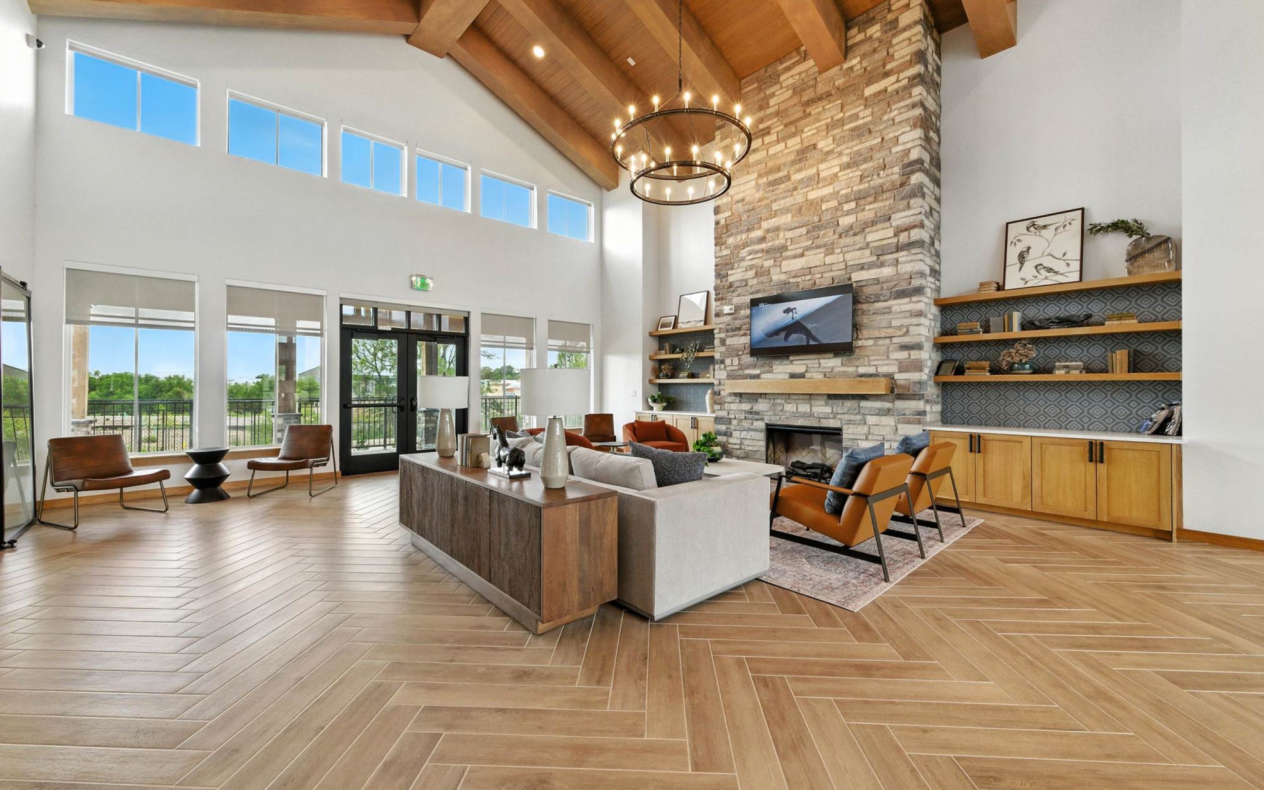 Spacious clubhouse lounge at Ryder Ridge featuring vaulted wood-beam ceilings, a stone fireplace, and comfortable modern seating.