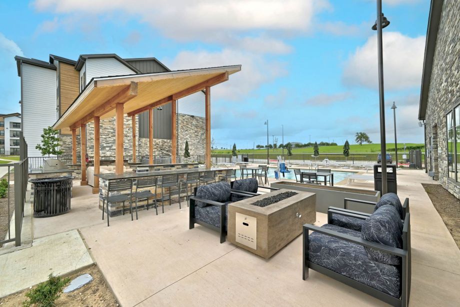 Outdoor seating area at Ryder Ridge featuring modern lounge chairs, a fire pit, and views of the community pool.
