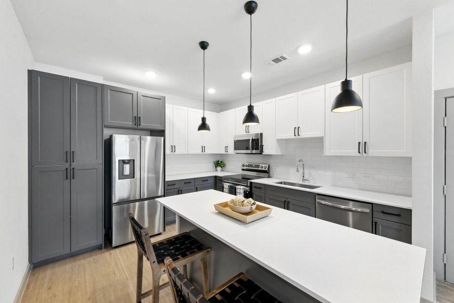 Modern kitchen at Ryder Ridge featuring quartz countertops, stainless-steel appliances, and black pendant lighting.