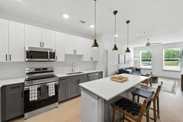 Modern kitchen at Ryder Ridge featuring stainless-steel appliances, pendant lighting, and a spacious island with seating.