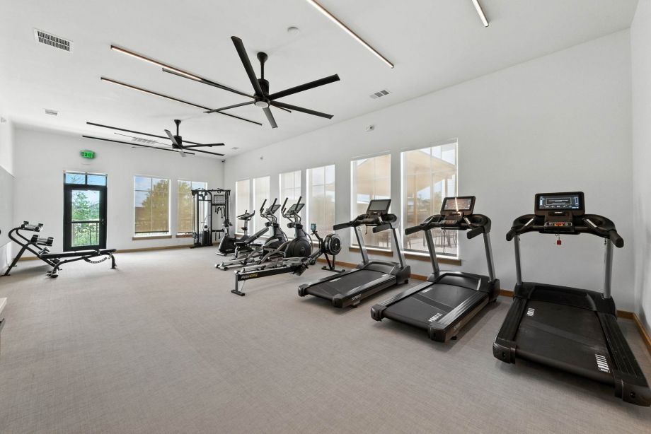Fitness center at Ryder Ridge featuring treadmills, stationary bikes, and large windows for natural light.
