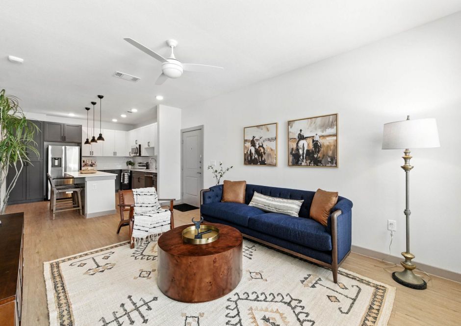Modern living room at Ryder Ridge featuring a navy sofa, wood coffee table, and open kitchen layout with contemporary finishes.”