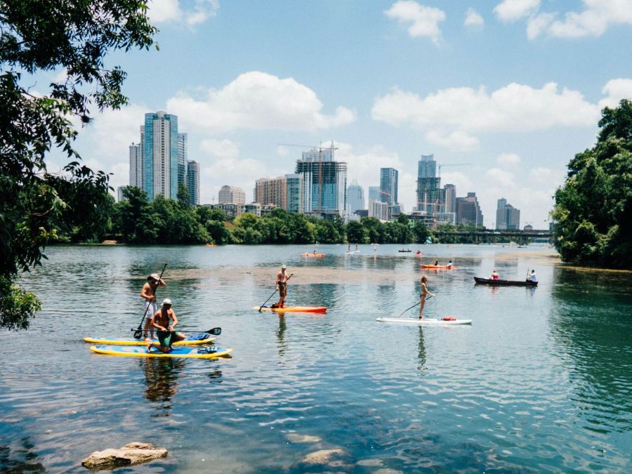 People paddleboarding on Lady Bird Lake in Austin, Texas, with the downtown skyline in the background near Ryder Ridge.