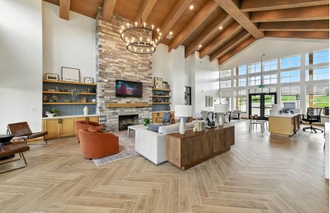 Modern clubhouse interior at Ryder Ridge featuring high ceilings, stone fireplace, and cozy lounge seating.