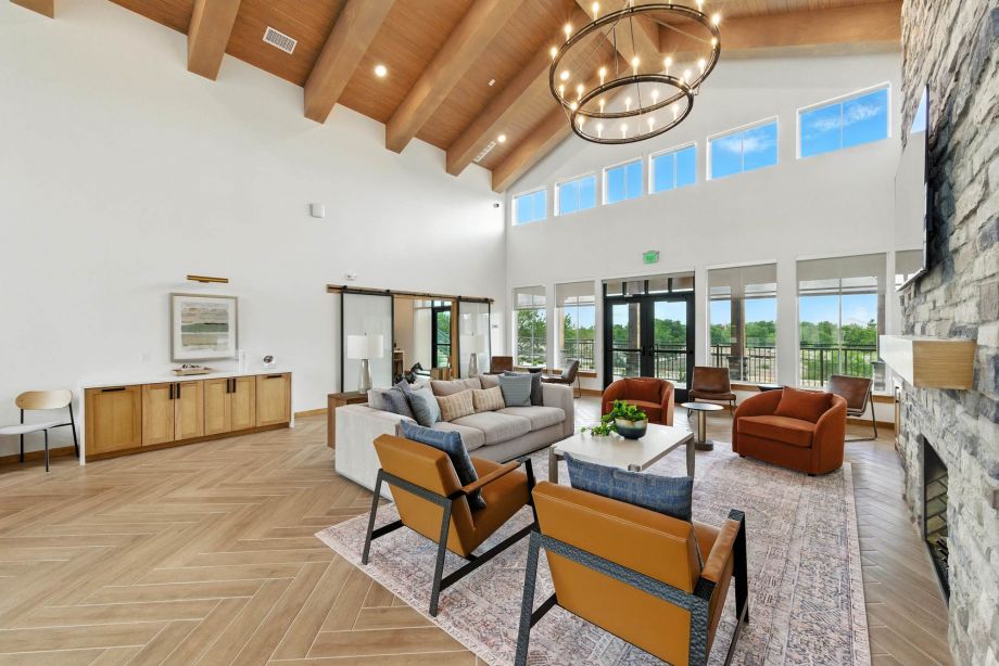 Spacious community lounge at Ryder Ridge featuring vaulted wood-beam ceilings, leather seating, and large windows with natural light.