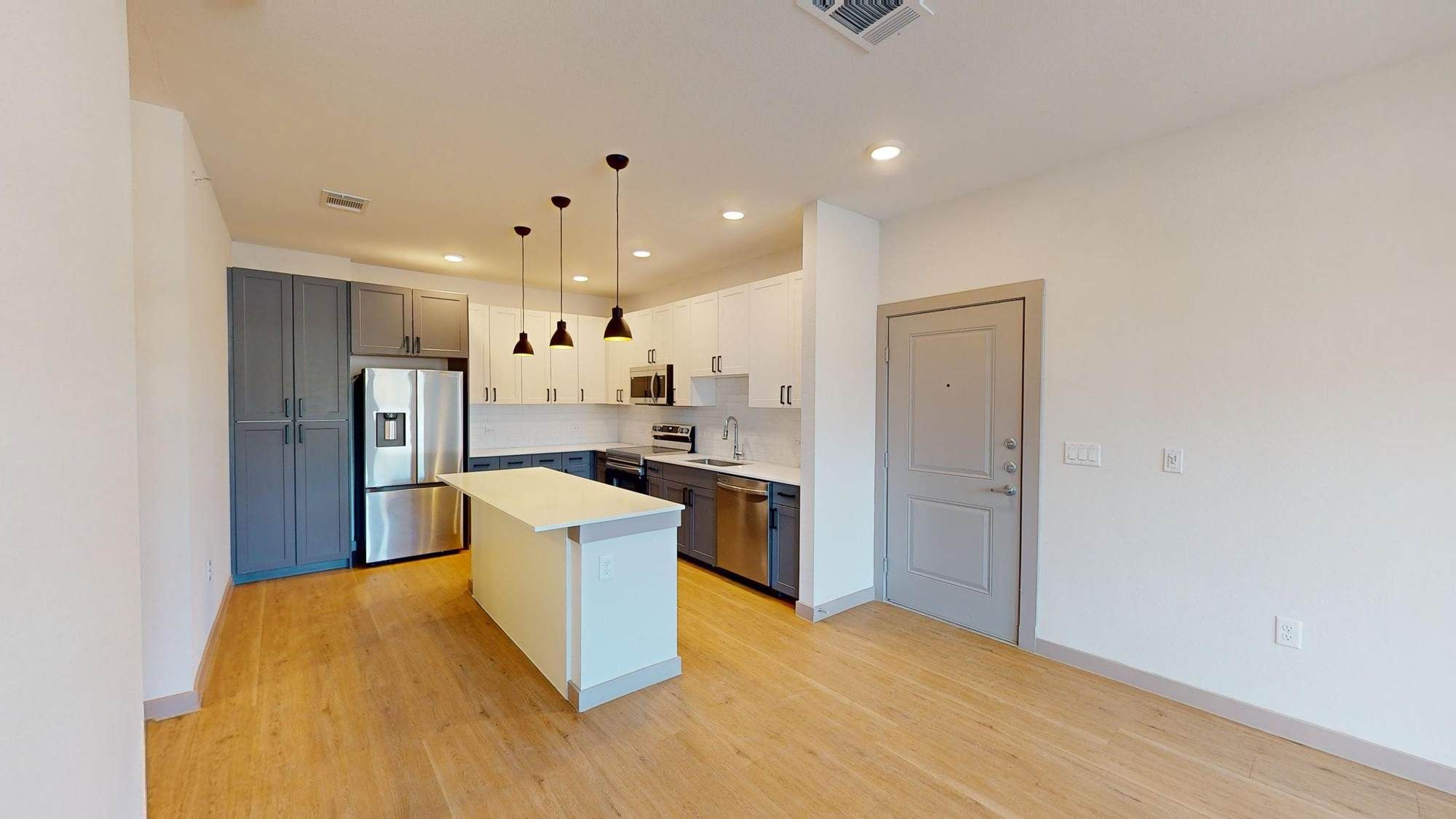 Spacious kitchen at Ryder Ridge featuring stainless-steel appliances, pendant lighting, and wood-style flooring.