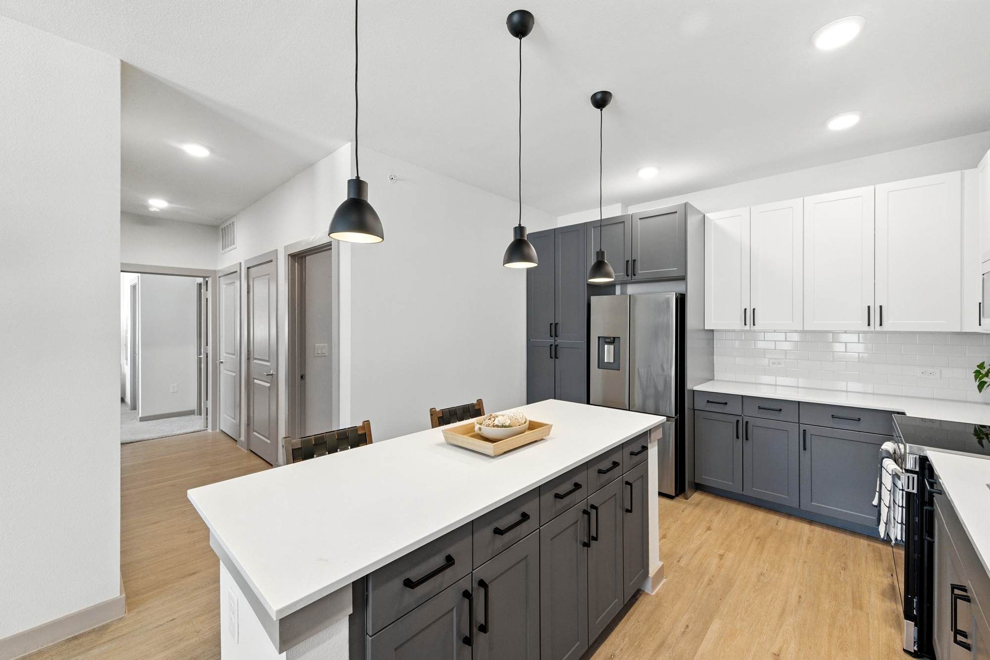 Spacious kitchen at Ryder Ridge featuring a large island with dark cabinetry, pendant lighting, and stainless-steel appliances.