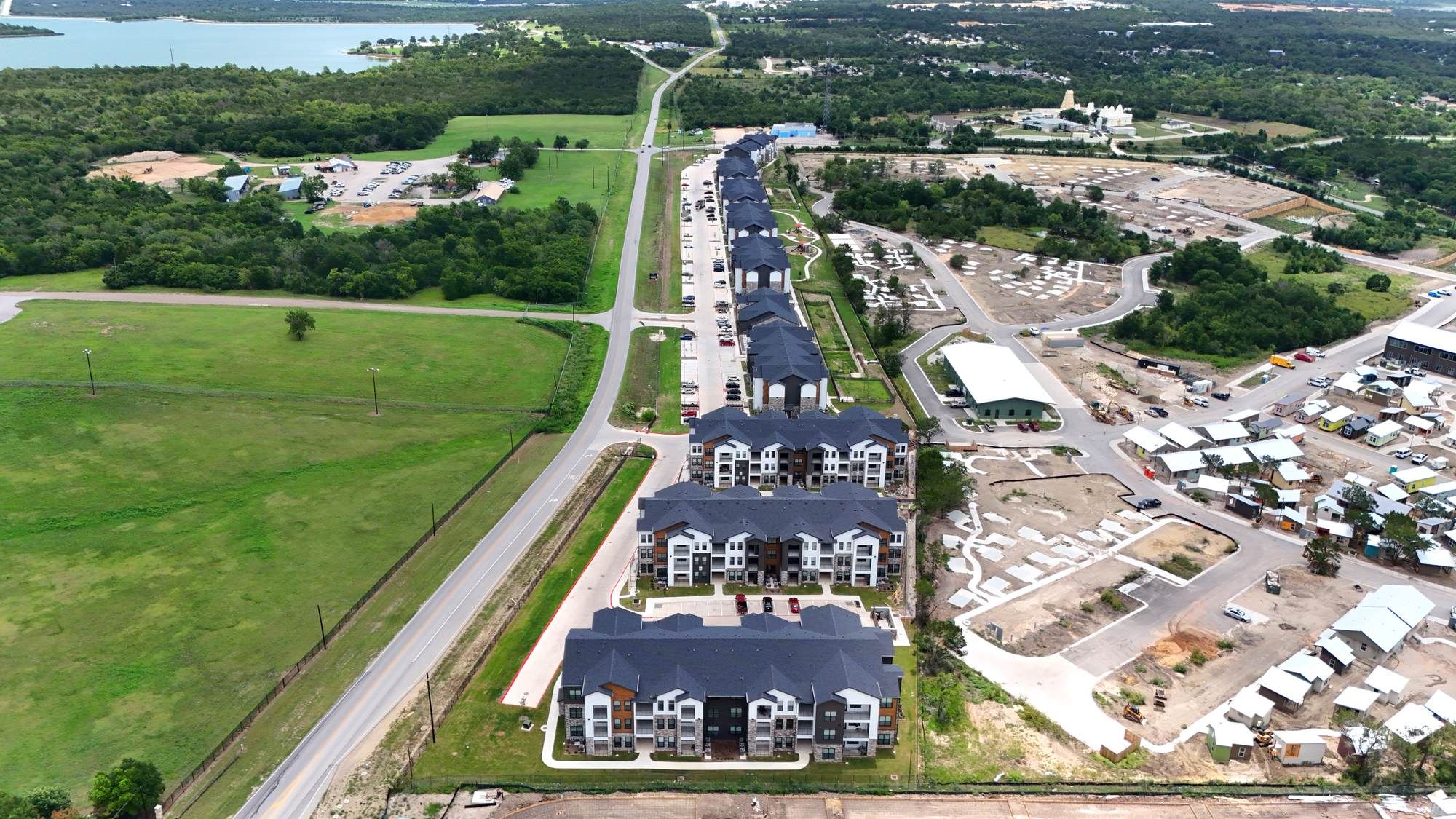 Aerial view of Ryder Ridge apartment community featuring modern buildings surrounded by open green fields and nearby roadways.