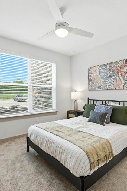 Bright bedroom at Ryder Ridge featuring a large window, modern ceiling fan, and neutral décor with soft natural light.