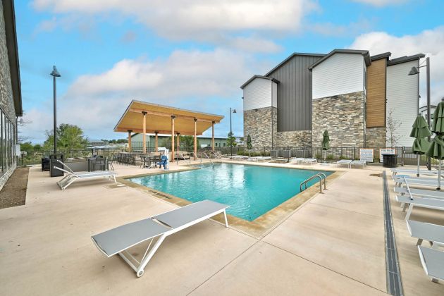 Resort-style pool at Ryder Ridge featuring modern lounge seating, stone accents, and a covered pavilion.