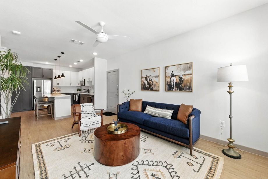 Modern living room at Ryder Ridge featuring a navy sofa, wood coffee table, and open kitchen layout with contemporary finishes.”